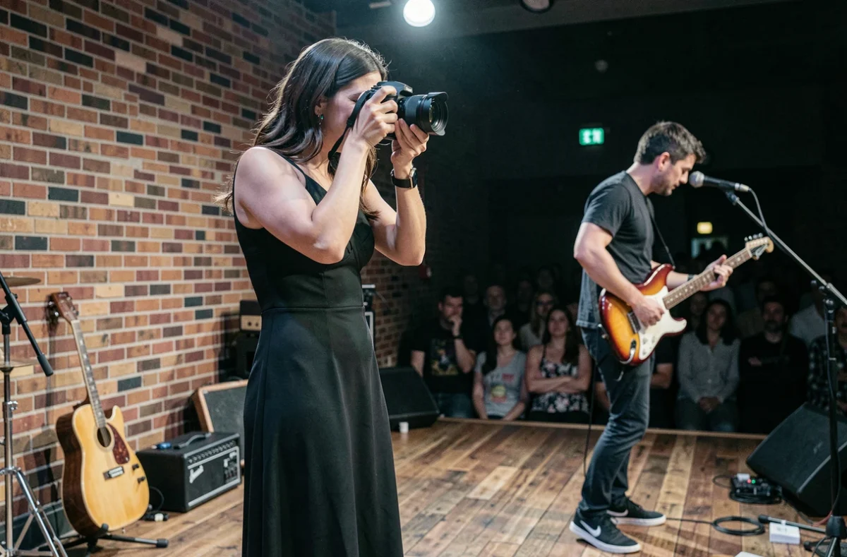 Photographe féminine capturant une performance musicale dans une salle de concert intimiste, représentant la spécialité de photographie musicale de Fanny Music Photography en Moselle